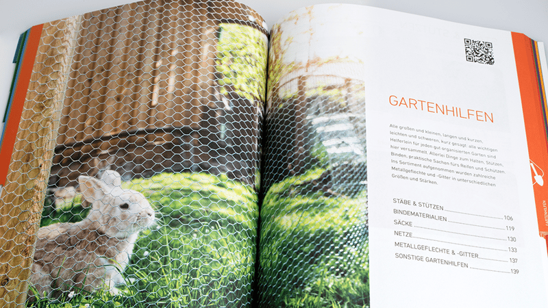 Aufgeschlagener Windhager-Katalog zeigt Kapitel 'Gartenhilfen' mit Foto eines Kaninchens hinter Maschendraht und Inhaltsverzeichnis rechts.